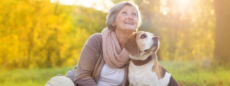 happy senior woman with pet dog beagle outside during fall season