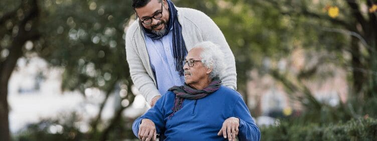 senior-hispanic-man-in-wheelchair-with-adult-son-outside