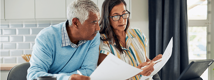 older-couple-sitting-at-kitchen-table-reviewing-financial-documents