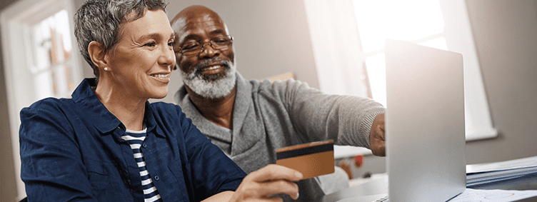 senior-couple-using-a-credit-card-and-laptop-while-working-on-their-finances-at-home