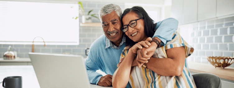 Happy senior couple at home using technology.