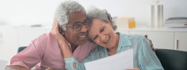 senior man and woman couple at home with laptop happily reviewing paperwork together