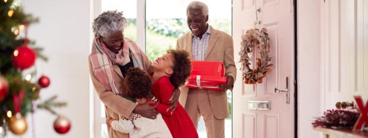 grandparents and grandchildren meet at the door with holiday gifts